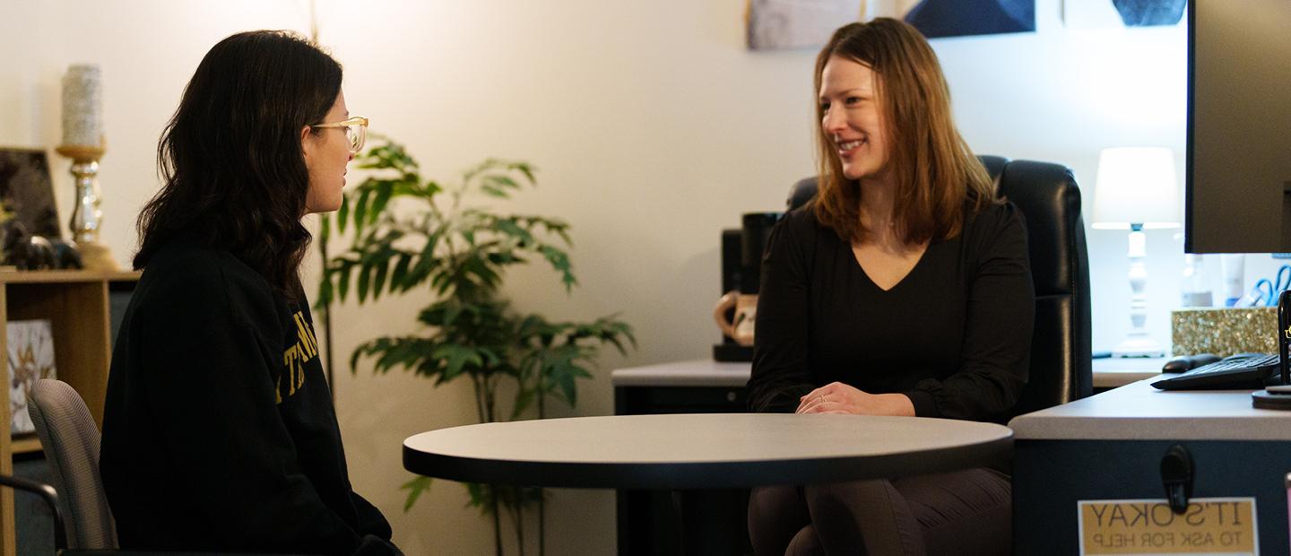 Young woman sits at table with an adviser.